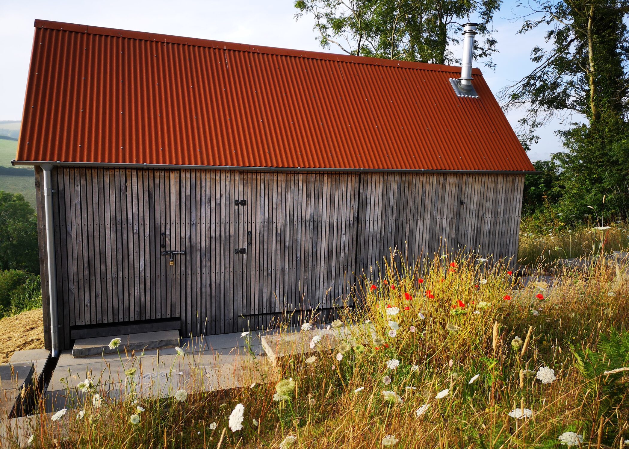 Woodcutters Refuge designed to look like an agricultural barn when shut up. Vertical oak cladding, corten roof and galvinised Lindab guttering