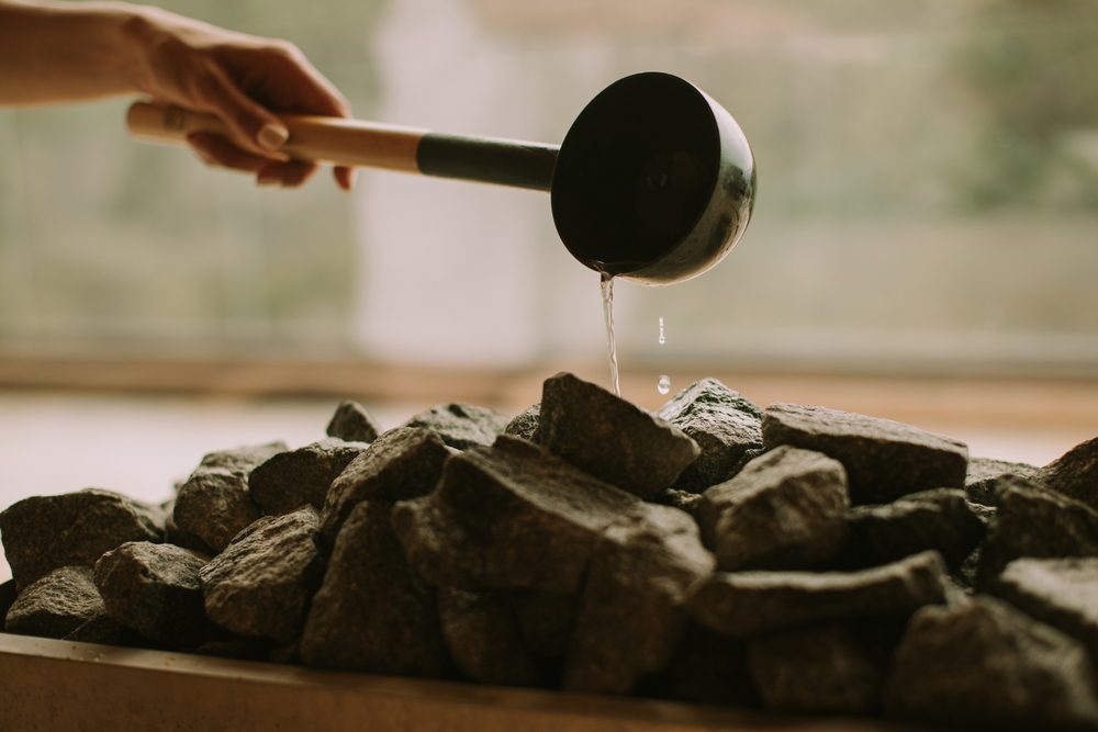 Pouring water on hot rocks in a sauna